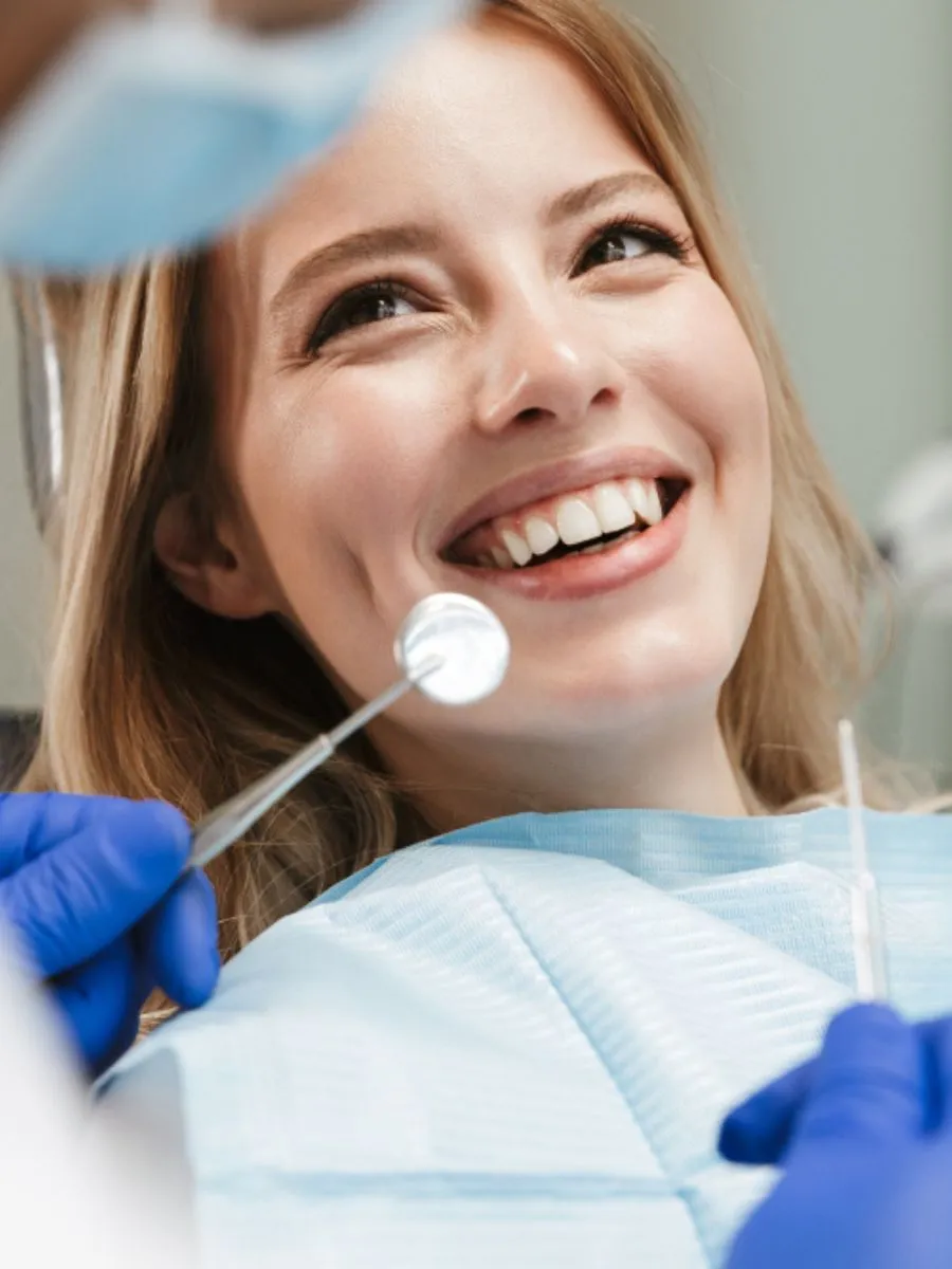 Smiling female patient during a dental check-up, receiving care from a dentist