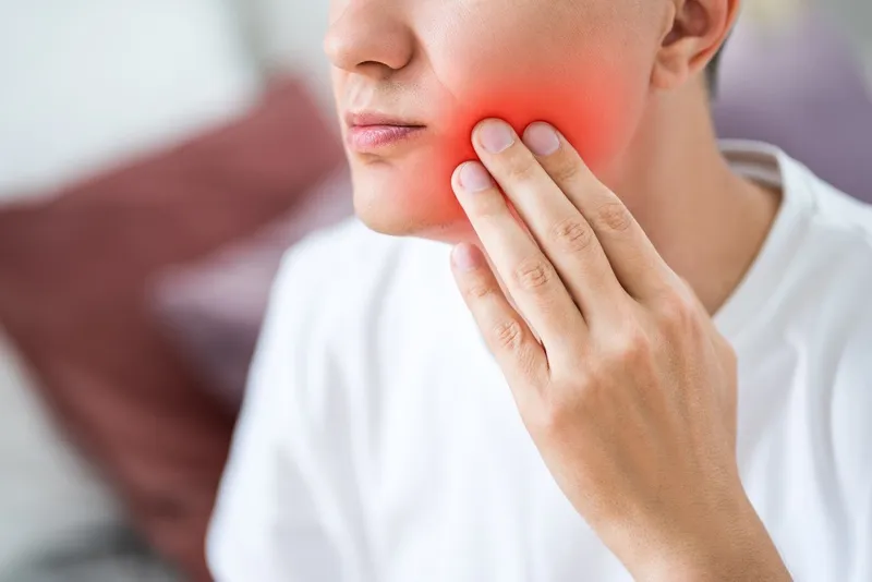 A man with toothache, periodontal disease in wisdom teeth, painful area highlighted in red