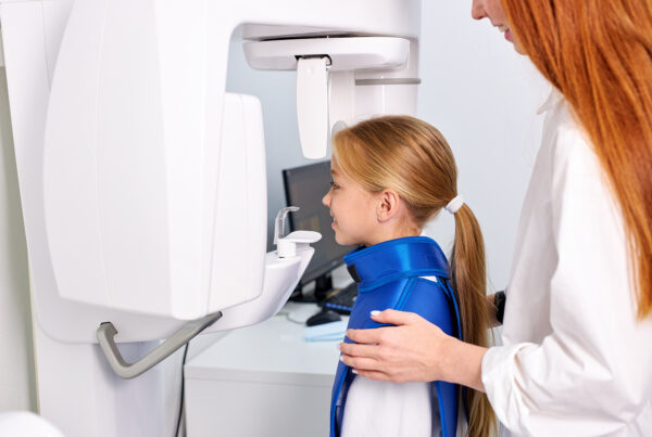 Woman dentist taking teeth x-ray of child patient using modern dental equipment.