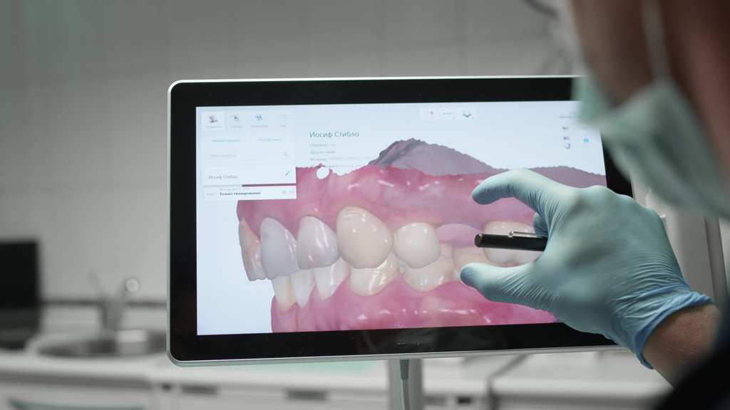 A professional dentist man looks at a 3d model of teeth on a computer monitor. Dental consultation, diagnostics. Jaw scan, digital imprint, medical digital technology.