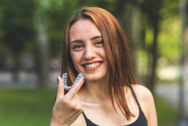 Beautiful smiling Turkish woman is holding an invisalign bracer with vibrant colors