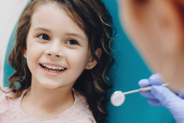 Curly haired little girl looking and smiling to the dentist after a checking up