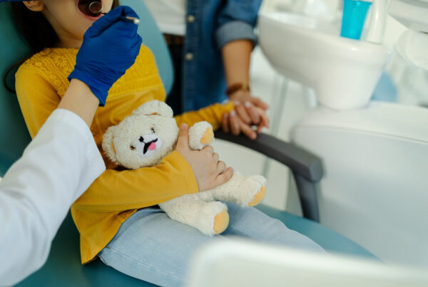 Mother holding the hand of her daughter who is visiting the dentist and thus supporting her.