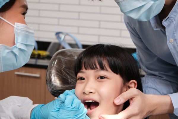 Pediatric dentist examining a young girl's teeth during a checkup